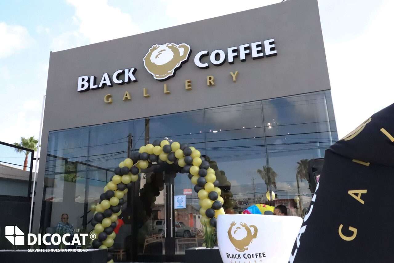 Fachada de Black Coffee Gallery el día de la apertura, con un arco de globos verdes y negros en la entrada.