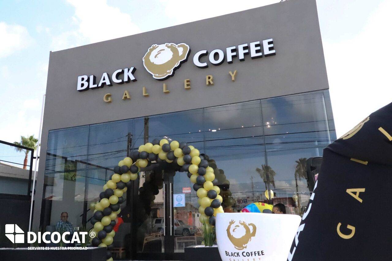 Fachada de Black Coffee Gallery el día de la apertura, con un arco de globos verdes y negros en la entrada.