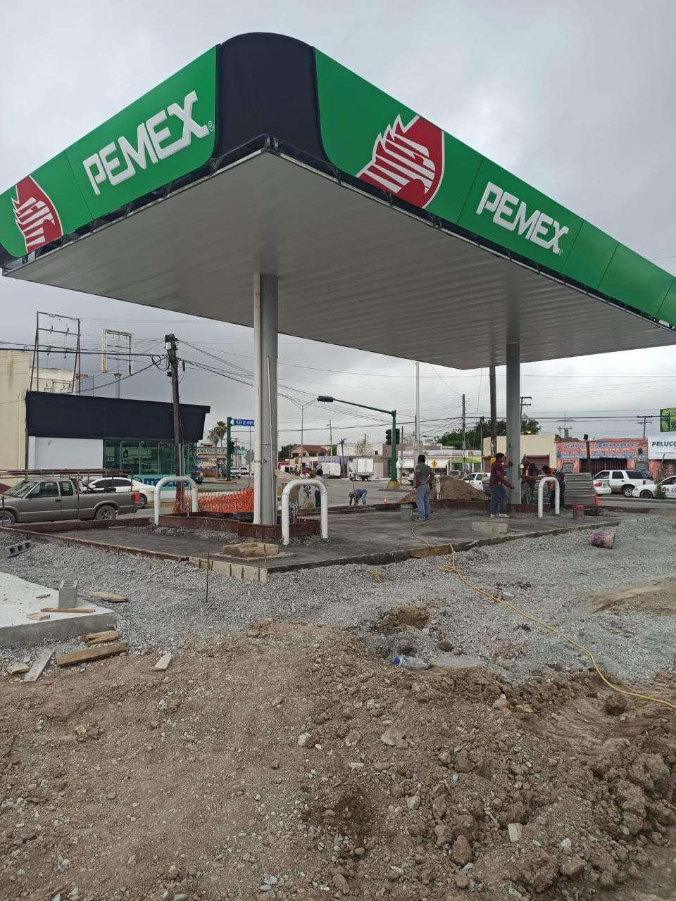 Marquesina verde y roja de una estación de servicio Pemex terminada, vista desde el patio de despacho con las islas ya colocadas.