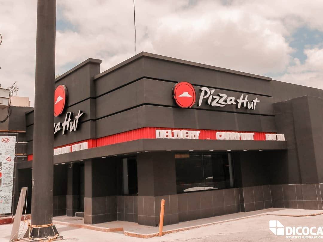 Edificio de dos niveles con una sucursal de Pizza Hut en planta baja y el anuncio de letra volumétrica montado sobre la fachada.