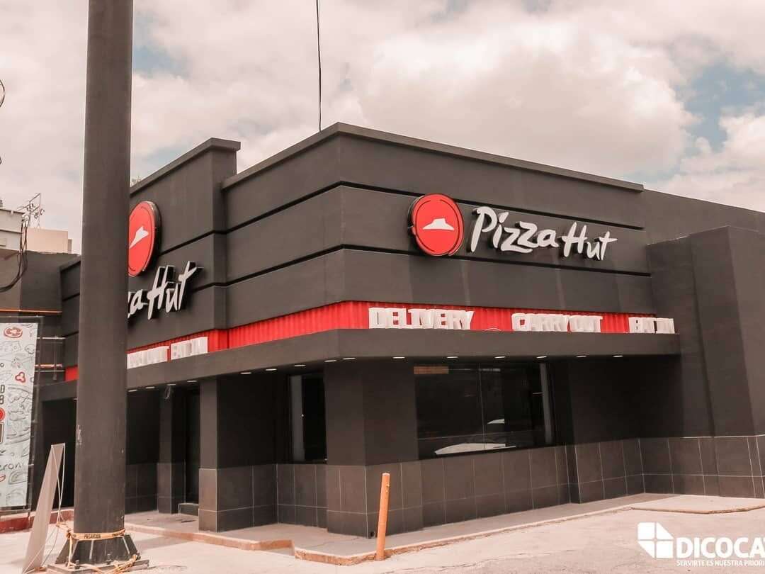 Edificio de dos niveles con una sucursal de Pizza Hut en planta baja y el anuncio de letra volumétrica montado sobre la fachada.
